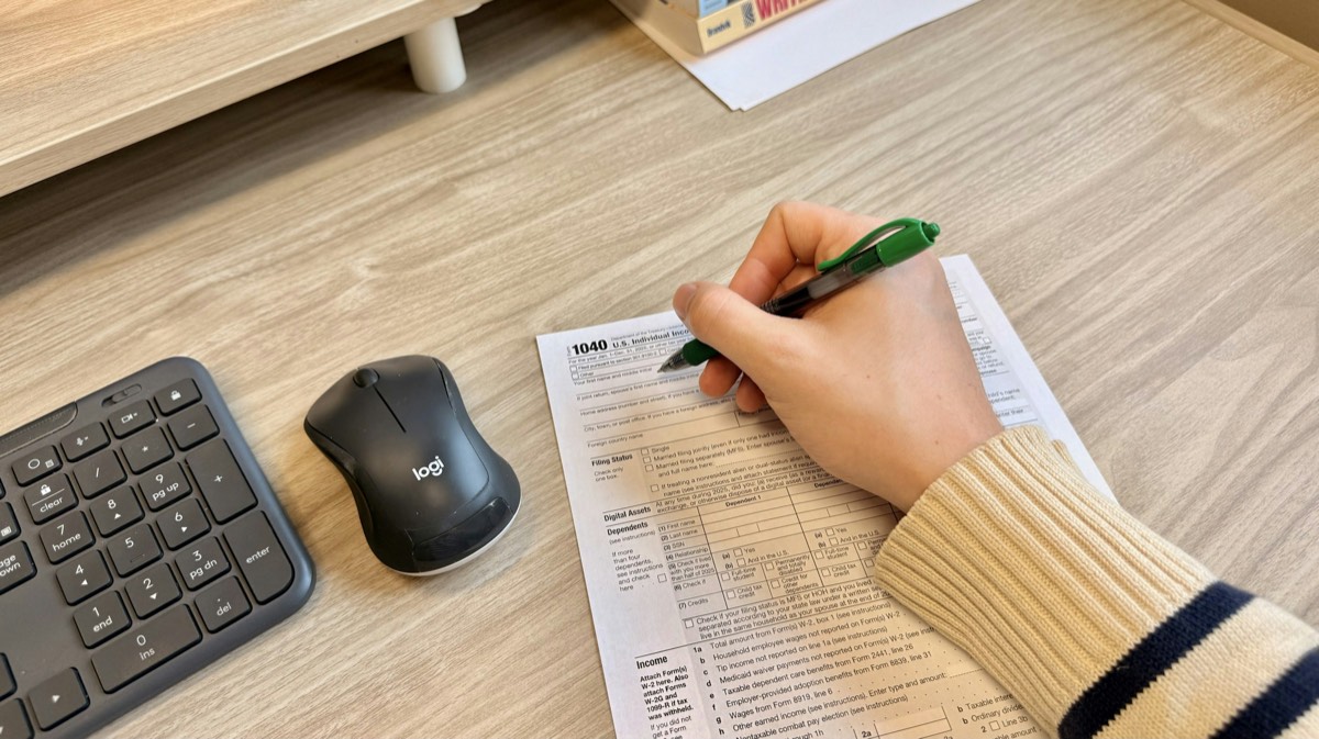 Eine Hand füllt mit einem grünen Stift ein Formular aus.